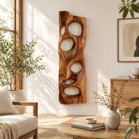 Wooden wall art panel with irregular oval cutouts in a bright sunroom with green plants