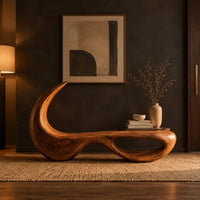 Sculpted bench with a hooked back and an open loop base in a dark entryway at golden hour
