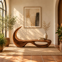 Sculpted bench with a hooked back and an open loop base in a bright entryway with arched windows and plants