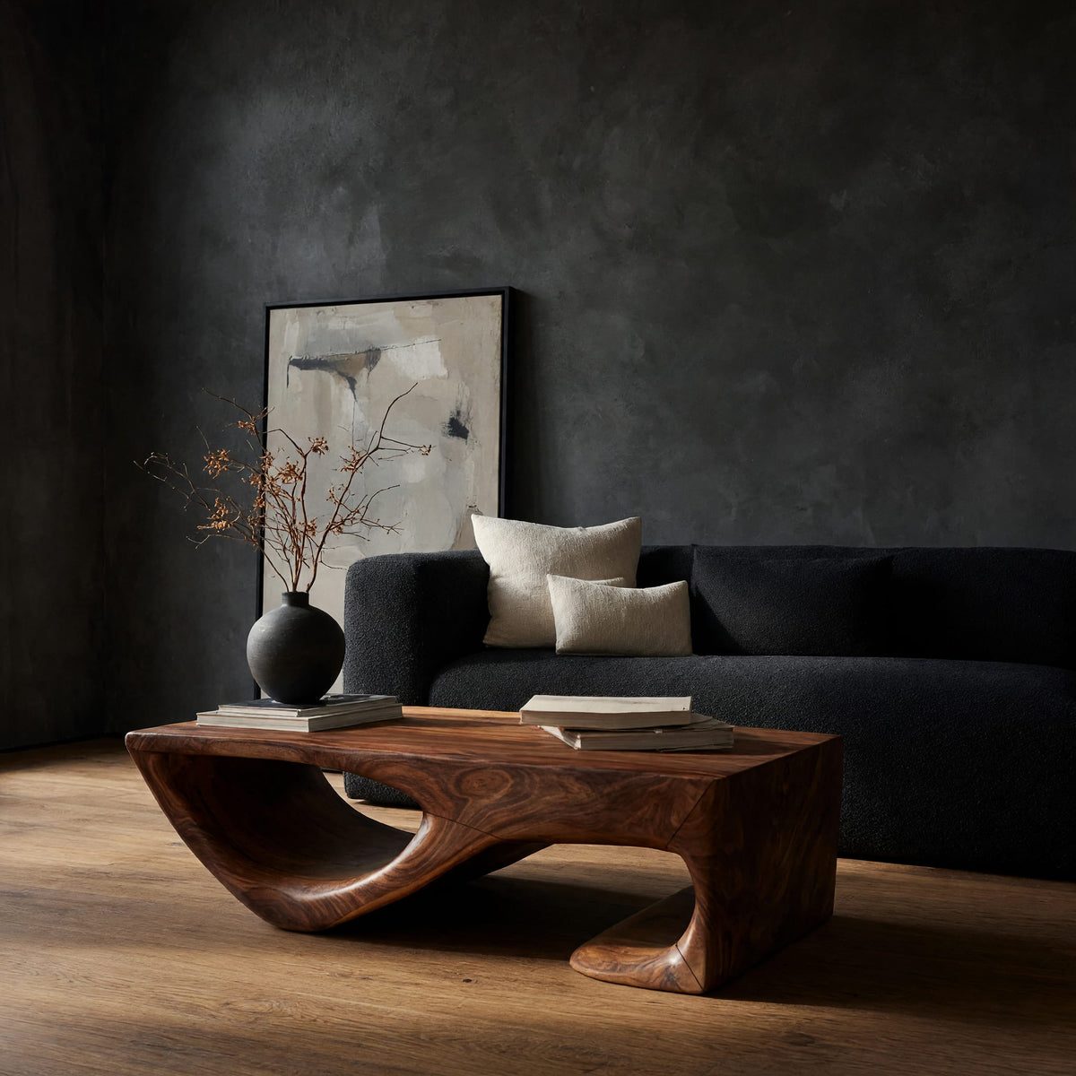 Dark coffee table with a scooped hollow and hooked end in a dark studio against a charcoal wall