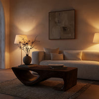 Dark coffee table with a scooped hollow and hooked end in an evening room lit by two lamps