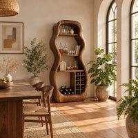 Freeform hourglass cabinet with open shelves and a grid of square cubbies in a bright dining room with arched windows and plants