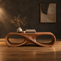 Coffee table shaped as an infinity loop with two oval openings in a dark studio against a charcoal plaster wall