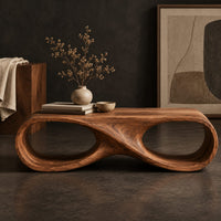 Corner detail of coffee table shaped as an infinity loop with two oval openings beside wood, brass and linen samples