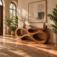 Console table shaped as an infinity loop with open ribbon spaces in a bright entryway with arched windows and plants