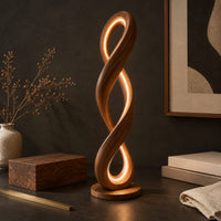 Corner detail of twisted infinity loop floor lamp with a glowing inner edge beside wood, brass and linen samples