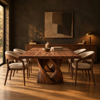 Rectangular dining table on a single pedestal of interlocking twisted ribbons in a dark dining room at golden hour