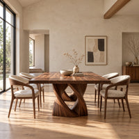 Rectangular dining table on a single pedestal of interlocking twisted ribbons in a bright open plan dining room