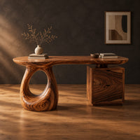 Kidney shaped desk with a loop pedestal and a two drawer cabinet in a dark studio against a charcoal plaster wall