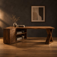 L shaped wood desk with ripple carved side unit and x shaped leg in a dark studio against a charcoal plaster wall