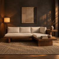 L shaped sofa with cream cushions on a low wood platform base in a dark living room at golden hour