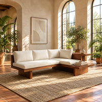 L shaped sofa with cream cushions on a low wood platform base in a bright living room with arched windows and plants