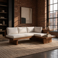 L shaped sofa with cream cushions on a low wood platform base in an industrial loft living room with exposed brick