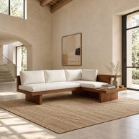 L shaped sofa with cream cushions on a low wood platform base in a bright open plan living room