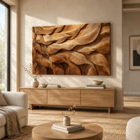 Rectangular wall art panel of layered carved leaves in deep relief above a light oak sideboard in daylight