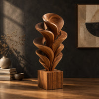 Wood sculpture of layered swirling petals rising from a square block base, three-quarter view showing the grain