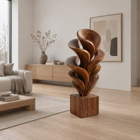 Wood sculpture of layered swirling petals rising from a square block base in a Scandinavian living room with white walls