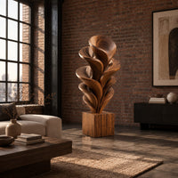 Wood sculpture of layered swirling petals rising from a square block base in an industrial loft living room with exposed brick