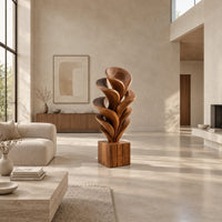 Wood sculpture of layered swirling petals rising from a square block base in a bright open plan living room