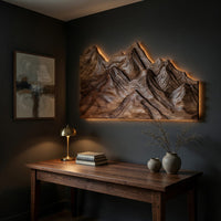 Layered ridge carved mountain wall art above a desk in a dark study corner