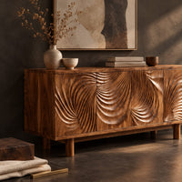Corner detail of sideboard with four layered swirl carved panels on sturdy legs beside wood, brass and linen samples