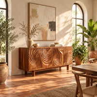 Sideboard with four layered swirl carved panels on sturdy legs in a bright dining room with arched windows and plants