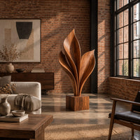 Wood sculpture of sweeping leaf blades rising from a square block base in an industrial loft living room with exposed brick