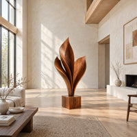 Wood sculpture of sweeping leaf blades rising from a square block base in a bright open plan living room
