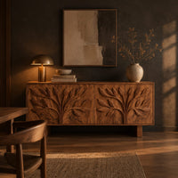 Low sideboard carved with two leafy branch trees across four doors in a dark dining room at golden hour