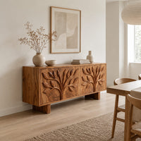 Low sideboard carved with two leafy branch trees across four doors in a Scandinavian dining room with white walls