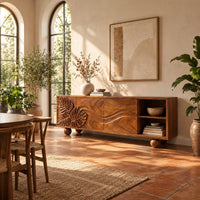Sideboard with leaf carved doors, ball feet and an open shelf bay in a bright dining room with arched windows and plants