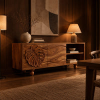Sideboard with a carved leaf door, open shelf bay and ball feet in an evening dining room with walnut wall paneling