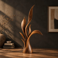 Wood sculpture of layered leaf blades rising from one tapered base, three-quarter view showing the grain