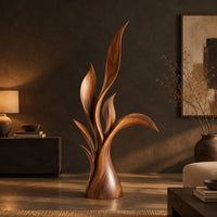 Wood sculpture of layered leaf blades rising from one tapered base in a dark living room at golden hour