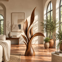 Wood sculpture of layered leaf blades rising from one tapered base in a bright living room with arched windows and plants