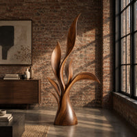 Wood sculpture of layered leaf blades rising from one tapered base in an industrial loft living room with exposed brick