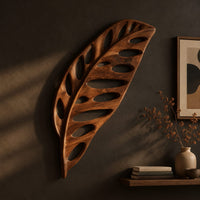 Leaf shaped wooden wall sculpture with open oval cutouts and carved veins, three-quarter view showing the carved depth