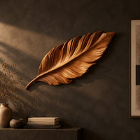 Leaf shaped wooden wall sculpture with raised carved veins and a curling stem on a dark charcoal plaster wall