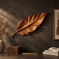 Detail of leaf shaped wooden wall sculpture with raised carved veins and a curling stem beside wood, brass and linen samples