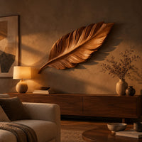 Leaf shaped wooden wall sculpture with raised carved veins and a curling stem above a low console in an evening living room