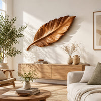 Leaf shaped wooden wall sculpture with raised carved veins and a curling stem in a bright sunroom with green plants
