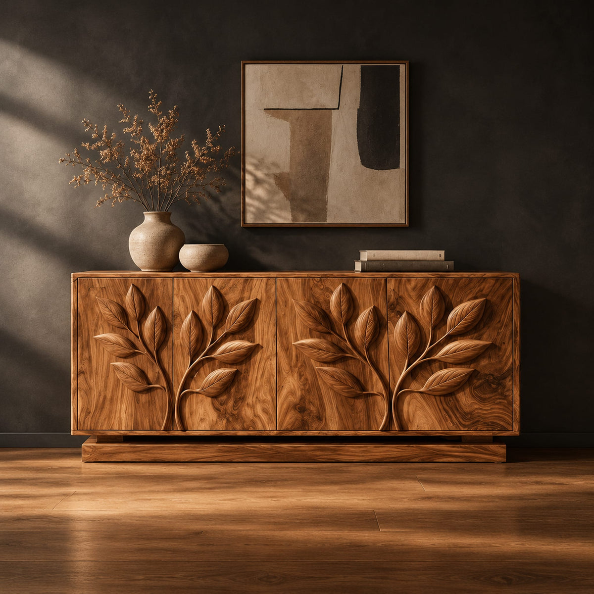 Sideboard with two carved leafy branches across four doors on a plinth in a dark studio against a charcoal plaster wall