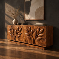 Sideboard with two carved leafy branches across four doors on a plinth, three-quarter view showing the grain