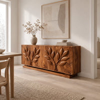 Sideboard with two carved leafy branches across four doors on a plinth in a Scandinavian dining room with white walls