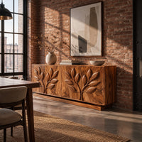 Sideboard with two carved leafy branches across four doors on a plinth in an industrial loft dining room with exposed brick