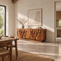 Sideboard with two carved leafy branches across four doors on a plinth in a bright open plan dining room