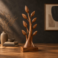 Tree shaped wood sculpture with leaf tips and a flared trunk in a dark studio against a charcoal plaster wall