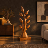Tree shaped wood sculpture with leaf tips and a flared trunk in a dark living room at golden hour