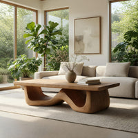 Light toned coffee table with a wave shaped base in a sunlit room with large windows and plants