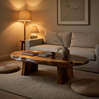 Thick live edge slab coffee table on block pedestals in an evening room lit by two lamps